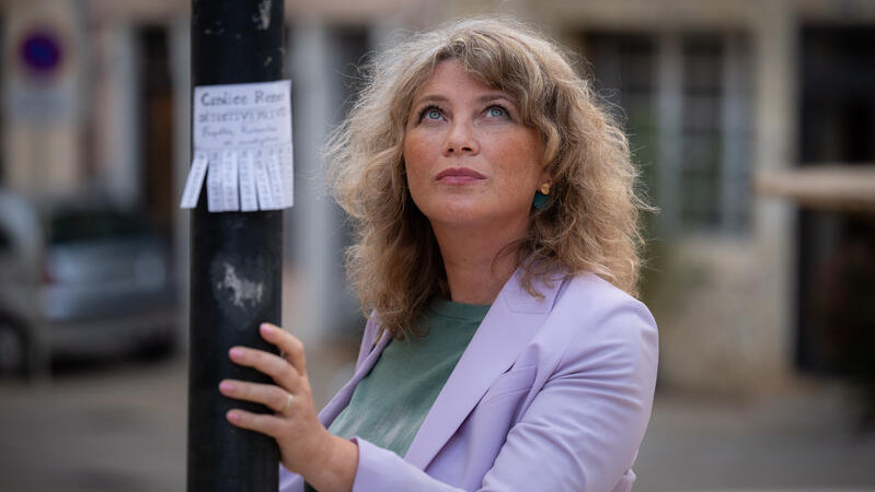 Cécile Bois se tenant à un lampadaire sur lequel apparaissent des étiquettes détachables à son nom